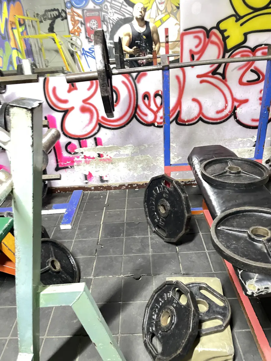 Discos y barras frente a una pared con grafitis en Magnum Gym