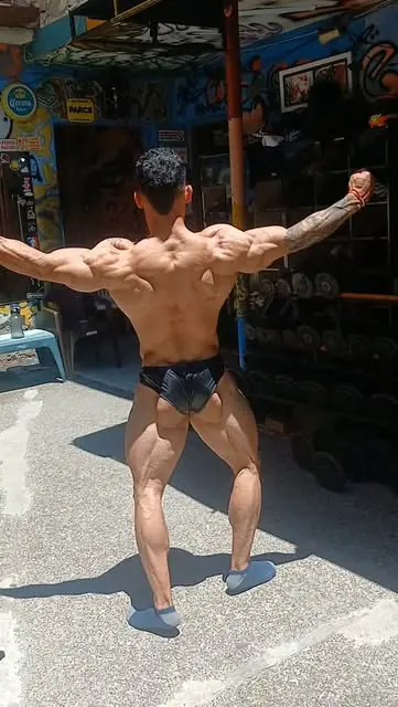 Culturista posando de espaldas en el patio del gimnasio