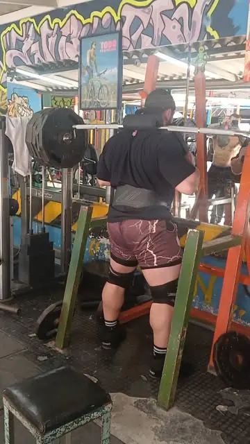 Atleta haciendo sentadilla en el rack, frente a una pared con grafitis